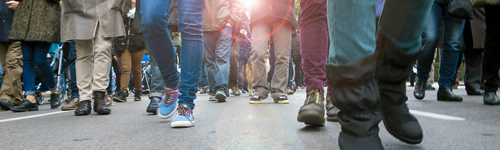 image from the waist down of a crowd of people walking in the street