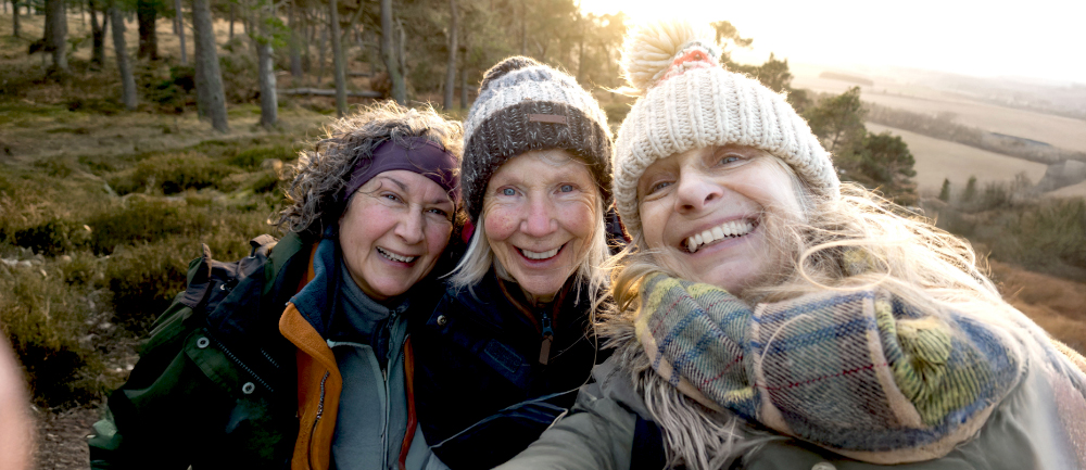 Selfie of three smiling women on a sunny, wintery hike