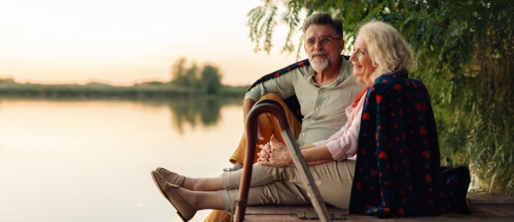Smiling man and woman sitting on a dock, relaxing at sunset